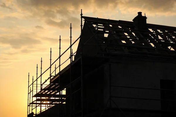 Échafaudage contre une maison en cours de réfection de toiture, en contre-jour