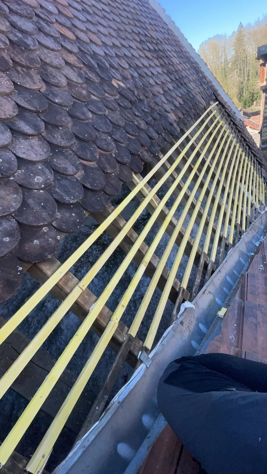 Pose de liteaux et de tuiles plates sur une toiture en cours de réfection